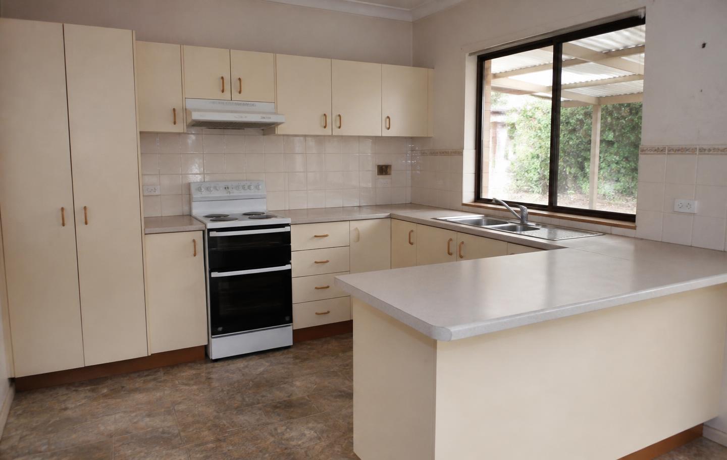 Dated 1990s kitchen with cream laminate cabinetry before renovation